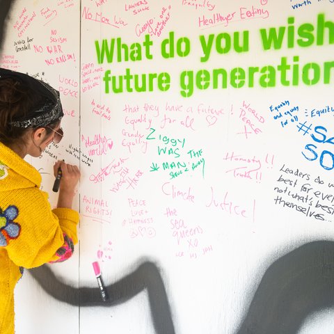 A festivalgoer adds their wish to the wall in Oxfam's stand at the joint charities meeting space at Glastonbury.