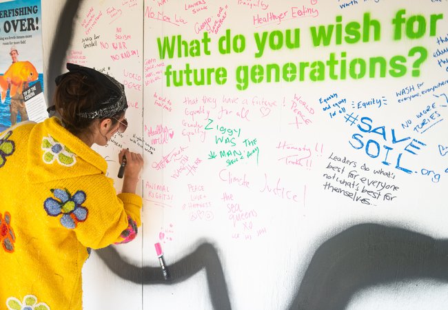 A festivalgoer adds their wish to the wall in Oxfam's stand at the joint charities meeting space at Glastonbury.