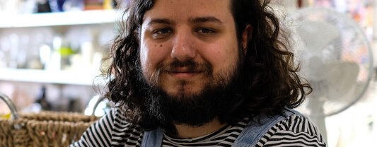 A man sitting on a stool smiling at the camera.
