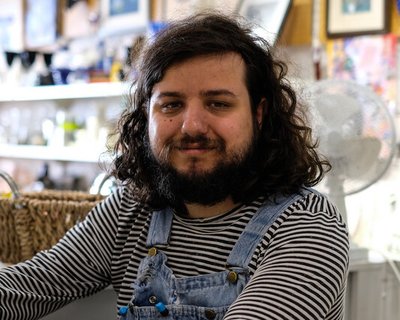A man sitting on a stool smiling at the camera.