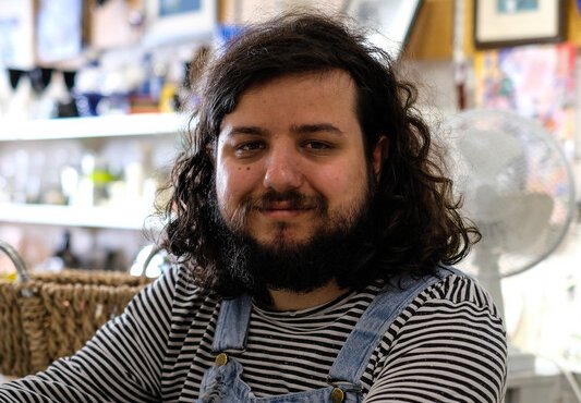 A man sitting on a stool smiling at the camera.