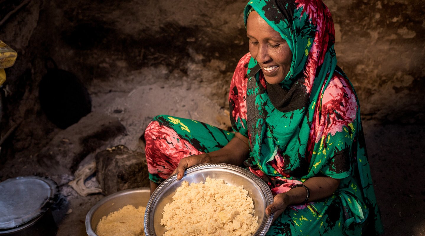 Safia in Kenya holds a dish of rice and potatoes.