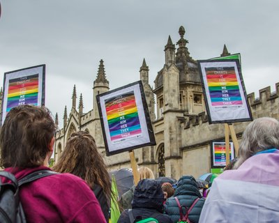 Oxford Pride march featuring three Oxfam LGBTQIA+ placards which read: "this charity is for you me him her they them"