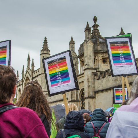 Oxford Pride march featuring three Oxfam LGBTQIA+ placards which read: "this charity is for you me him her they them"
