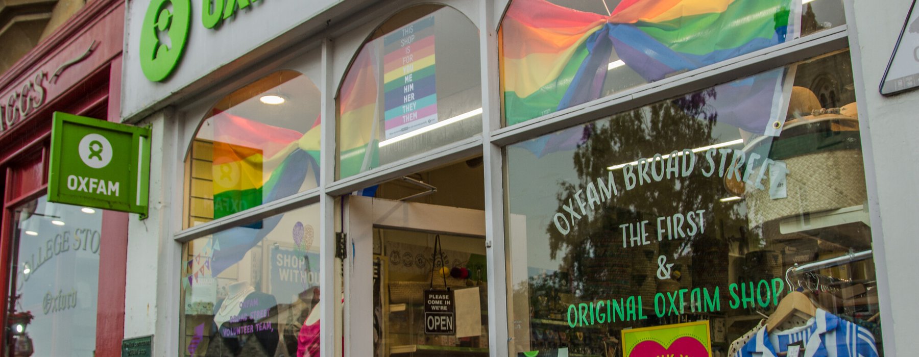 Pride flags and volunteer posters in window of Oxfam shop in Broad Street, Oxford,UK.