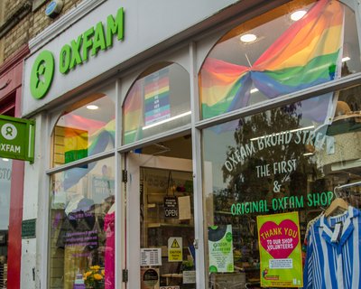 Pride flags and volunteer posters in window of Oxfam shop in Broad Street, Oxford,UK.