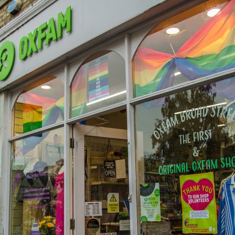 Pride flags and volunteer posters in window of Oxfam shop in Broad Street, Oxford,UK.