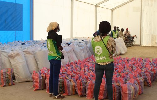 Oxfam staff in a tent in N'djamena, Chad looking at bags of food before distribution to the local community