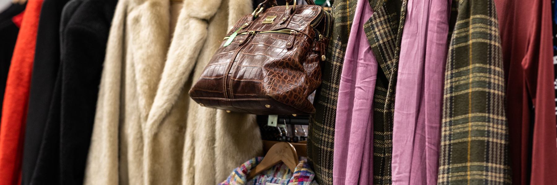 A check coat with pink scarf, a fur coat, a croc bag.