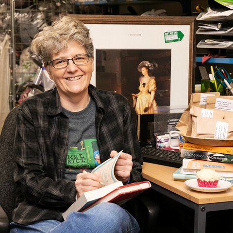 A woman sitting at a table making notes in a book