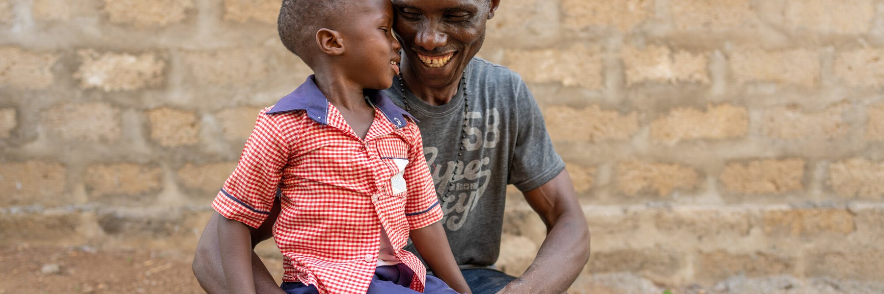 Nat spends time with his son Sorie* at the LAMBDA Poultry Farm in Maforki, Sierra Leone.