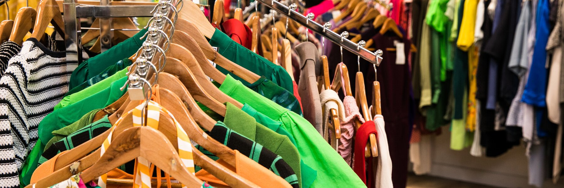 Racks of colourful women's clothes in an Oxfam shop.