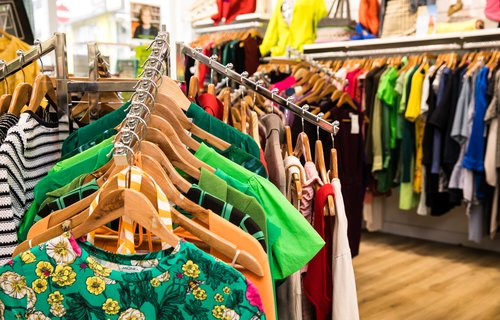 Racks of colourful women's clothes in an Oxfam shop.