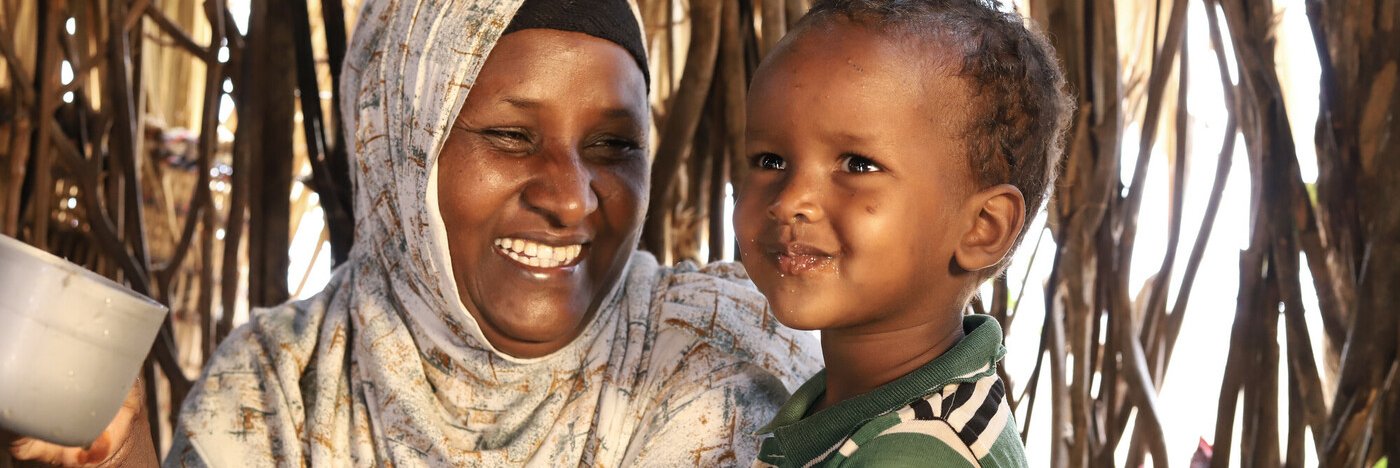 Abdia Ibrahim in Isiolo county, Kenyam drinks water with her son.