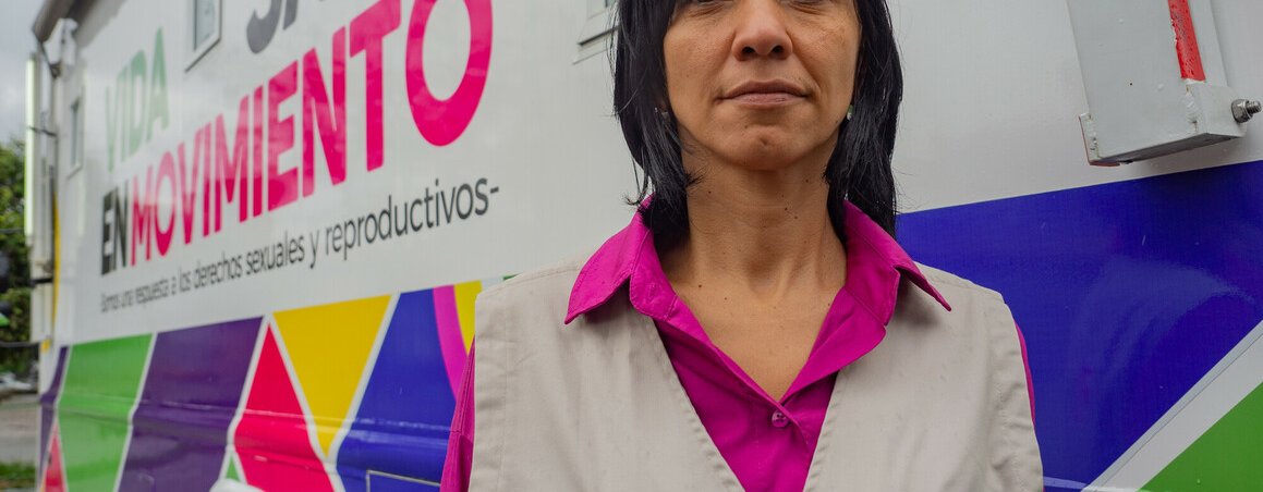 Johanna, a woman in an Oxfam-branded jacket, faces the camera as she stands outside a mobile reproductive health clinic in Columbia.