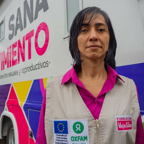 Johanna, a woman in an Oxfam-branded jacket, faces the camera as she stands outside a mobile reproductive health clinic in Columbia.