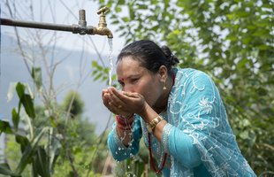 Urmila drinks from an Oxfam water tap in Dhading District, Nepal.