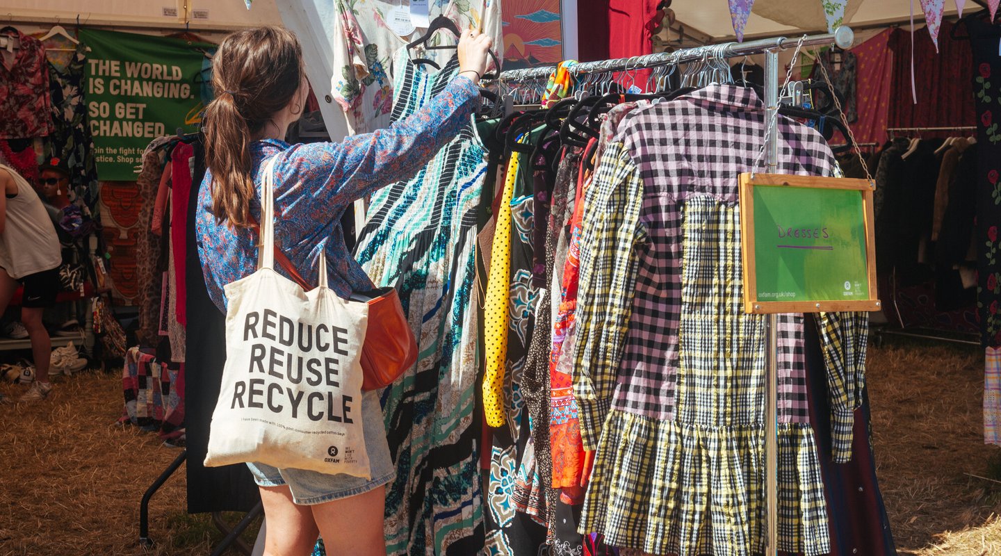 A woman browses second hand clothes at an Oxfam festival shop at Glastonbury 2023.