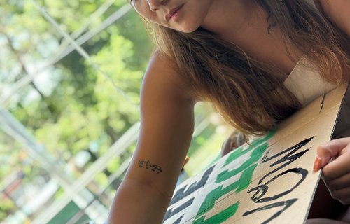 Marinel Ubaldo painting a climate justice placard