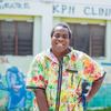 Peter is stood smiling in the centre of the image in front of the clinic with a hand on his hip.