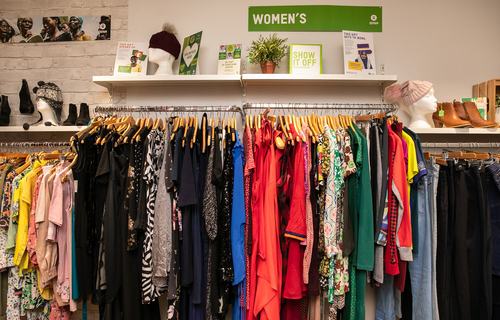 Rail of brightly coloured clothes inside an Oxfam shop