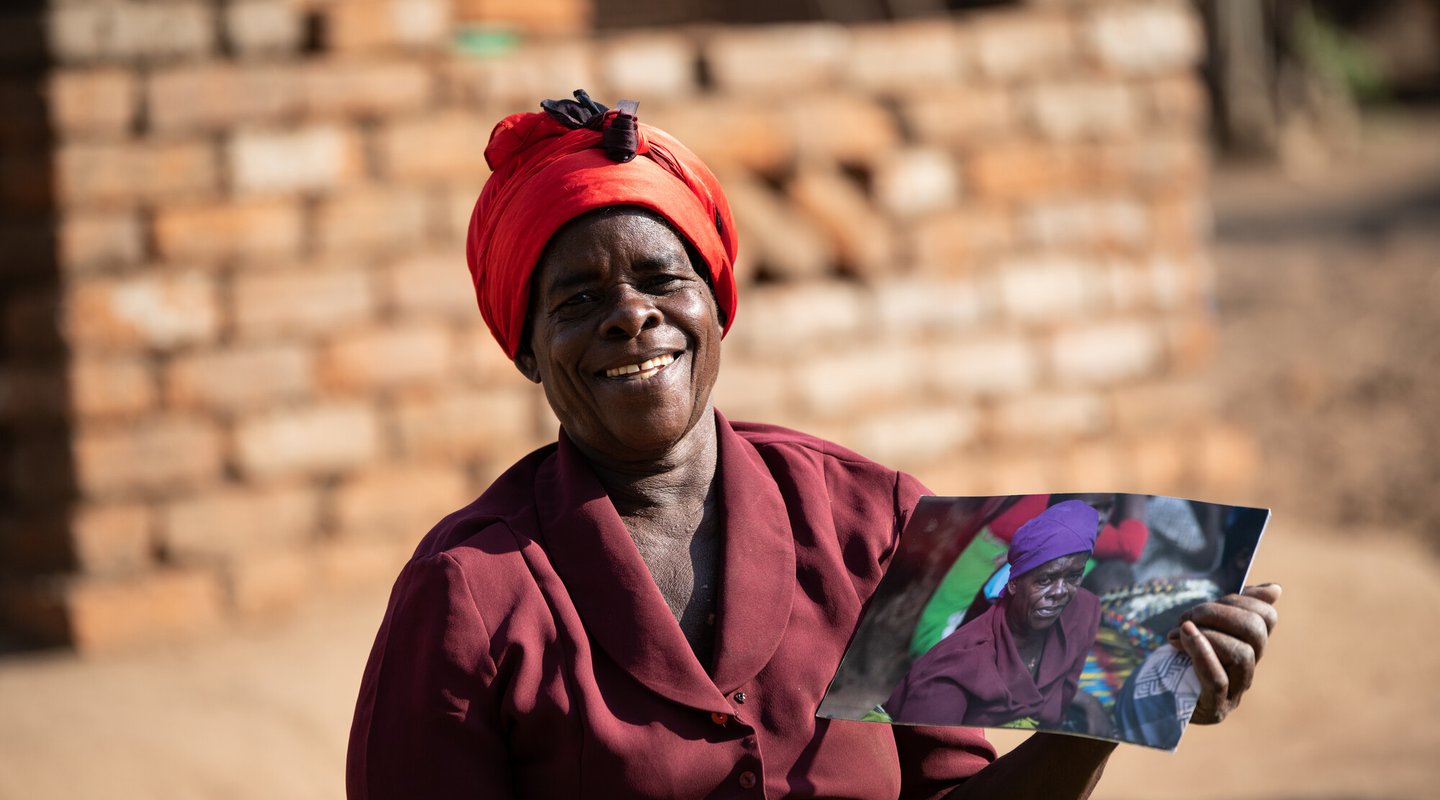 Ligineti Nayinayi, a Cyclone Freddy Survivor, is seen holding pictures taken in March 2023 soon after Cyclone Freddy hit at her village in Phalombe, Southern Malawi