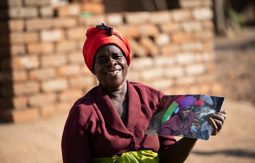 Ligineti Nayinayi, a Cyclone Freddy Survivor, is seen holding pictures taken in March 2023 soon after Cyclone Freddy hit at her village in Phalombe, Southern Malawi