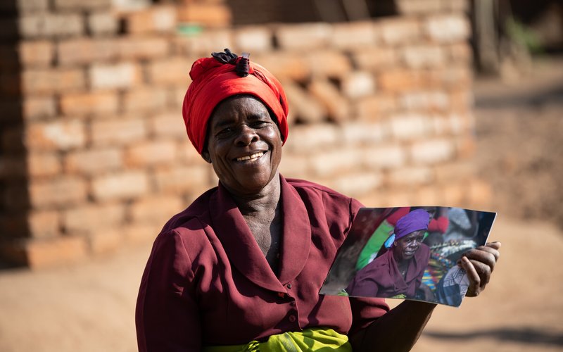 Ligineti Nayinayi, a Cyclone Freddy Survivor, is seen holding pictures taken in March 2023 soon after Cyclone Freddy hit at her village in Phalombe, Southern Malawi