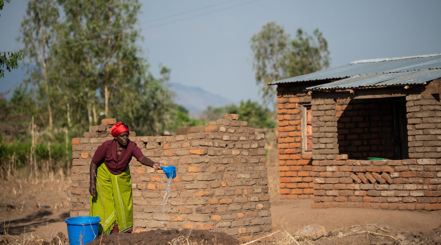 Ligineti watering mud for making bricks at her village in Phalombe, southern Malawi