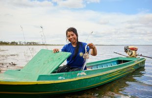Chhorvy, a community leader in Sesan, Cambodia, holds up her fishing nets as she sits in her boat.