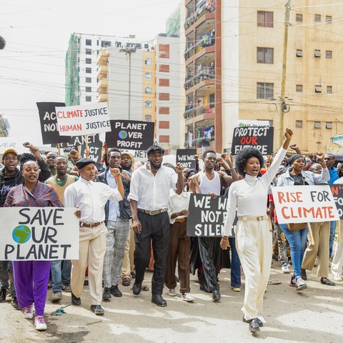 Protesters carry banners with messages like 'Save Our Planet' and 'Climate Justice' during a climate march in a city.