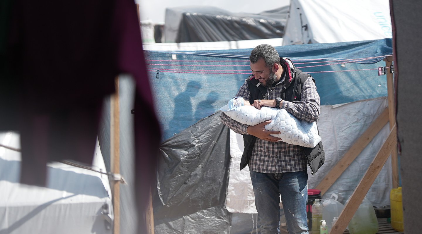 Fedaa holds his newly born baby boy in his tent in Tal Sultan in Rafah