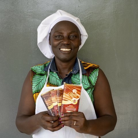 Smiling black woman wearing chef's hat looks directly at camera