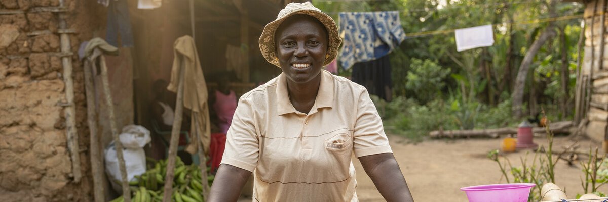 Smiling woman in centre of photo, there are lots of coca beans in front of her on a table
