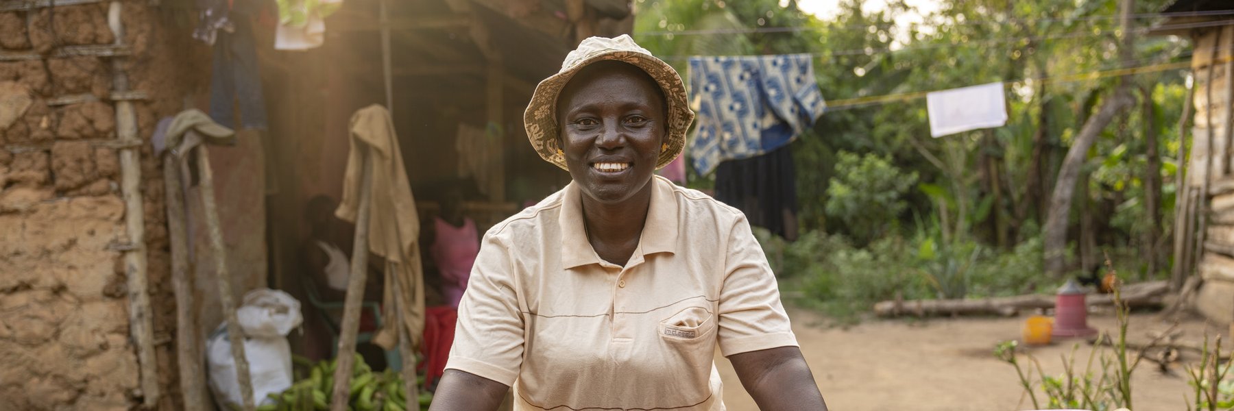 Leticia smiles as she stands behind a table of drying beans on at her farm in Ghana.