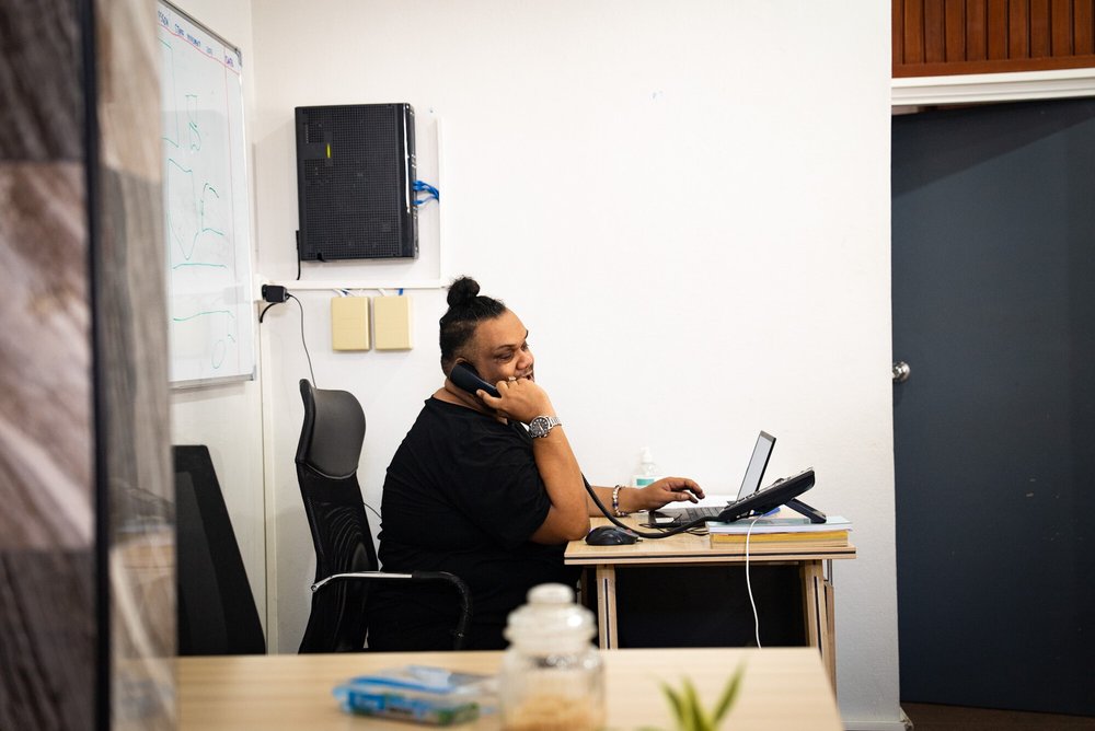 A person sitting at a desk, talking on a landline phone.