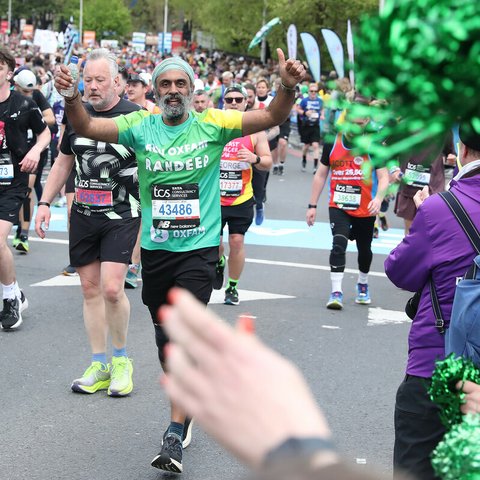 Oxfam supporter Randeep waving as he runs the 2024 London Marathon.