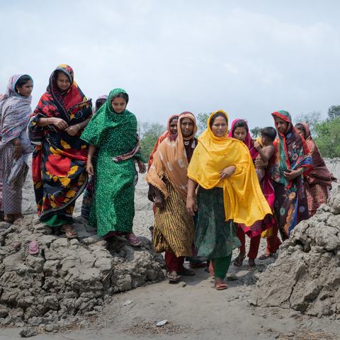 A group of women from a in Satkhira, Bangladesh walking along a rocky terrain impacted by climate change and increasing levels of salinity in the water.