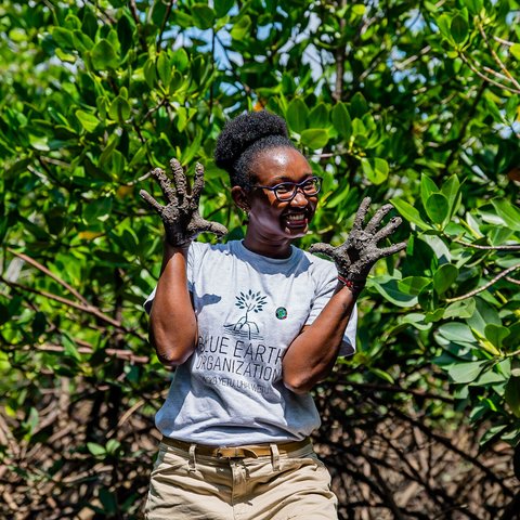 Joyce Koech poses for a photo with muddy hands in Mombasa County, Kenya.