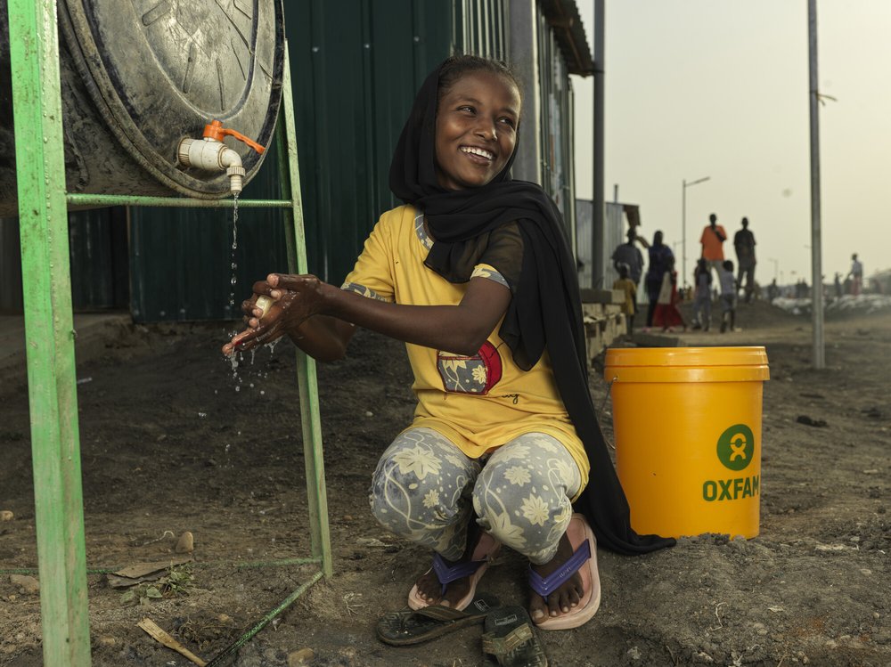Refugee Asia* washing her hand at an Oxfam supported WASH facility at their shelter at the transit center in Renk