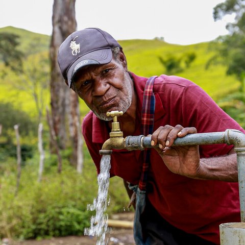 Esoi of Nogorunte community in Papua New Guinea, drinks water from a newly built tap outside his home.