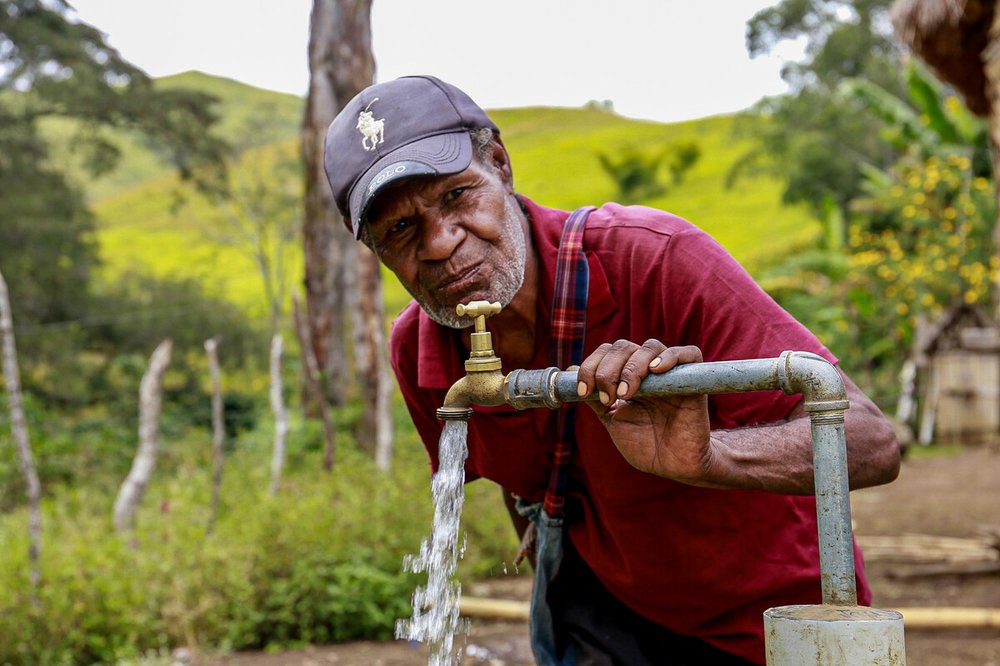 Esoi of Nogorunte community in Papua New Guinea, drinks water from a newly built tap outside his home.