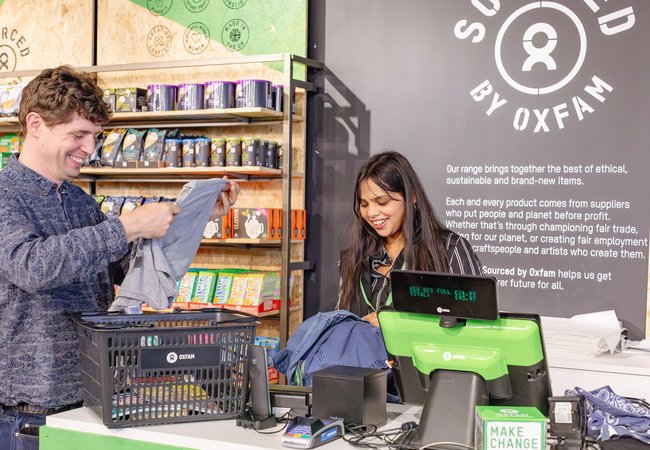 Richard and Mimansha smile as they work on the tills at Oxfam's Manchester Superstore.