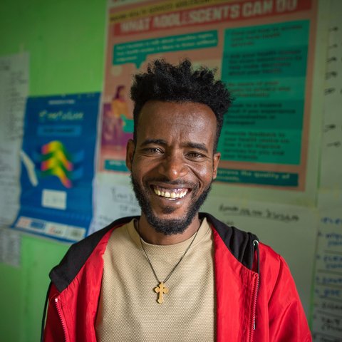 Aberaw Mamo, a smiling 24-year-old man in a red jumper, is a nurse in Birbir Ethiopia.