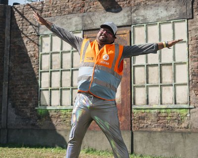 A man smiling wearing a high visibility waistcoat in the sunshine at a festival