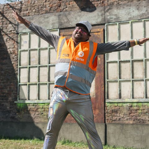 A man smiling wearing a high visibility waistcoat in the sunshine at a festival