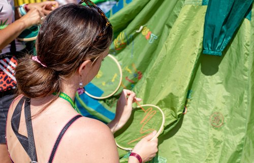 Oxfam steward, Paige Moncur, sewing embroidery as part of the dress project at Boardmasters festival.