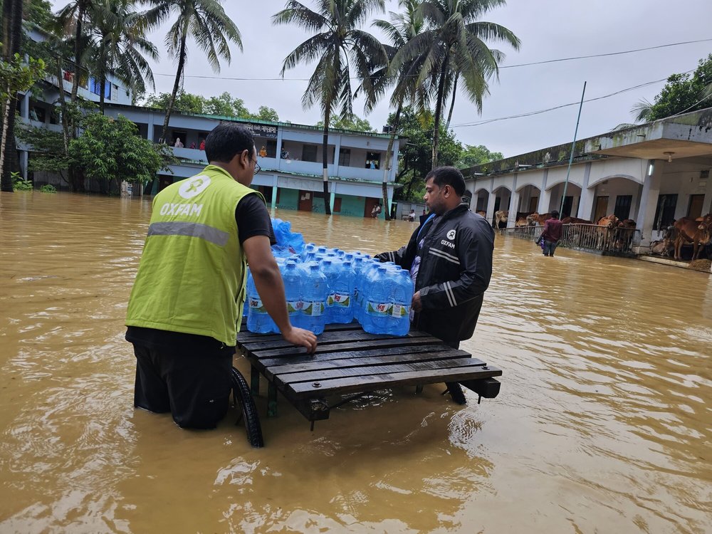 Two Oxfam staff members delivering essential clean water to flood-affected communities in the aftermath of the flooding in Bangladesh.