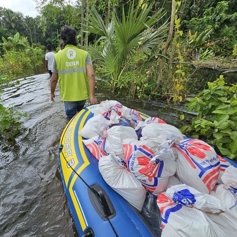 Oxfam teams navigating flooded areas with supplies in tow to reach those in desperate need in the aftermath of flooding in Bangladesh.