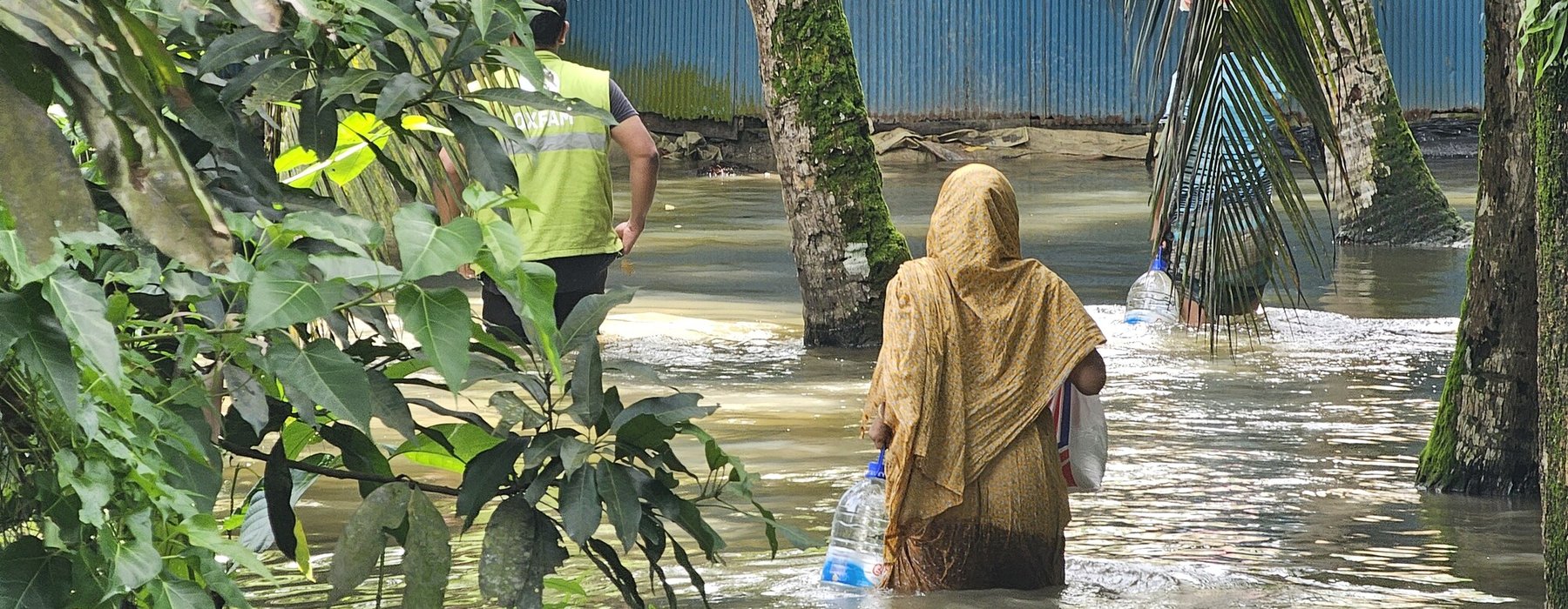 A woman receives essential supplies of clean water, ORS, and dry food provided by Oxfam in the aftermath of the 2024 Bangladesh floods.